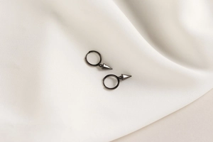 Detail of punk style black S925 silver hoop earrings with a sharp cone spike charm