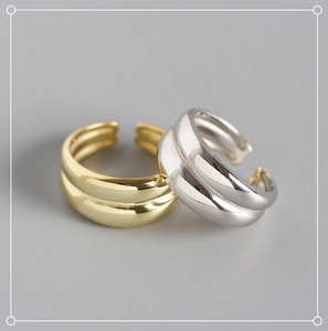 Dettaglio di anelli doppi aperti minimalisti in finiture lucide color oro e argento