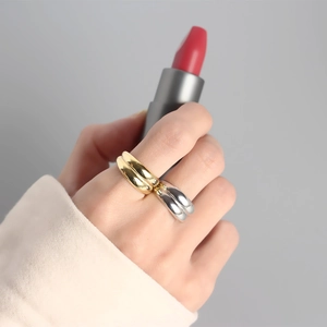 Primo piano di anelli larghi minimalisti in oro e argento indossati sull'indice