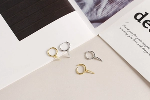 Macro detail of gold and silver hoop earrings with zircon-studded triangle pendants