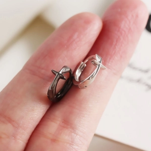 Créoles minimalistes en argent fin S925 avec pendentif croix présentées sur un doigt