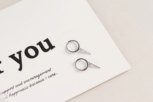 Detail of S925 silver hoop earrings with micro-set zircon triangle charms on card
