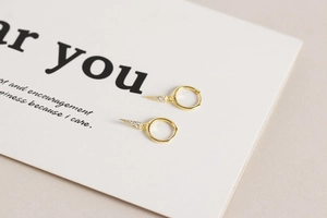 Close-up of gold s925 silver hoop earring with crystal-encrusted triangle pendant detail