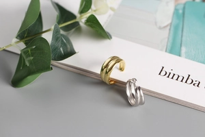 Dettaglio di anelli doppi minimalisti oro e argento appoggiati su una rivista