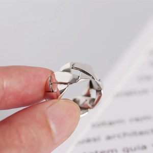 Detailed view of wide woven sterling silver ring with Cuban chain texture on fingers