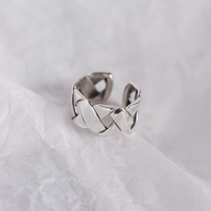 Detail of S925 sterling silver woven wide ring on a textured white paper background