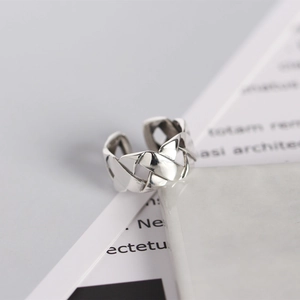 Macro detail of silver woven texture ring with interlocking hollow pattern design