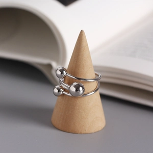 Macro detail of silver geometric wrap ring with bead accents on a wood display