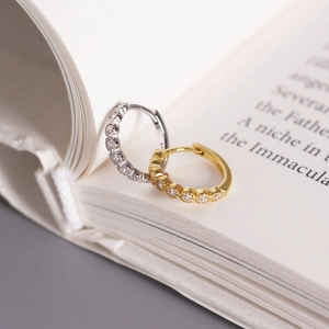 S925 sterling silver hoop earrings with pavé cubic zirconia on an open book