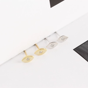 Detailed view of geometric eye-shaped silver and gold stud earrings with sparkling crystals