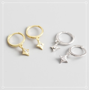 Macro shot of silver and gold geometric star dangle hoop earrings with cubic zirconia