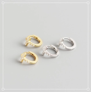 Macro shot of silver and gold cross hoop earrings with sparkling cubic zirconia inlay