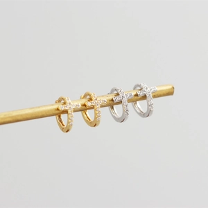 Detail view of gold and silver S925 sterling silver huggie earrings with zircon crosses