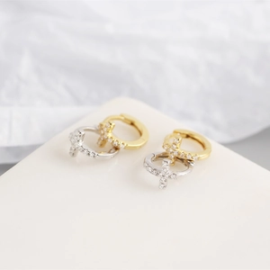 Detail of silver and gold cross hoop earrings with pave cubic zirconia settings