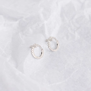 Close-up of minimalist S925 sterling silver hoop earrings with diamond cross pendants