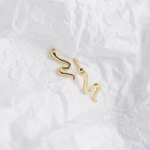 Detailed macro shot of golden snake stud earrings with tiny white zircon eyes