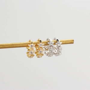 Detail of silver and gold huggie hoop earrings with star-shaped cubic zirconia clusters