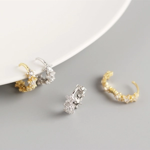 Detail of luxury S925 silver hoop earrings with shimmering gold and silver zircon stars