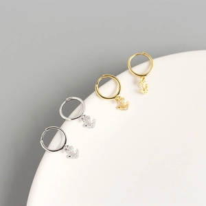 Makro-Detail von gold- und silbernen Anker-Creolen mit schimmernden Zirkonia-Anhängern