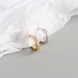 Detail van geometrische oorringen in goud en zilver met schitterende zirkonia steentjes