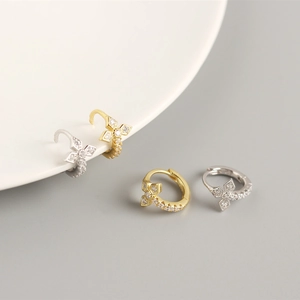Macro detail of S925 silver cross huggie earrings with sparkling cubic zirconia stones