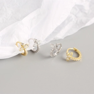 Close-up of gold and silver S925 sterling silver clover cross hoop earrings with crystals