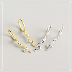 Macro shot of gold and silver S925 sterling silver snake earrings with tiny crystals