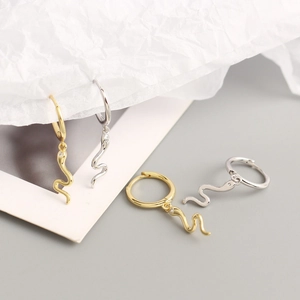 Elegant gold and silver snake hoop earrings with zircon accents on a minimalist background