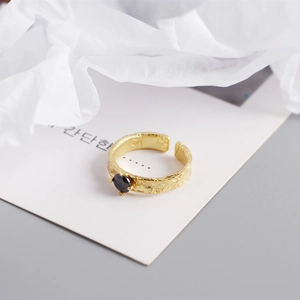 Détail d'une bague en argent doré avec texture lave martelée et pierre précieuse noire
