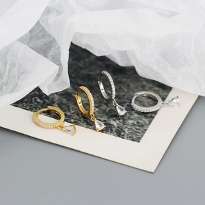 Detail of silver and gold teardrop earrings with pave zircons on elegant paper