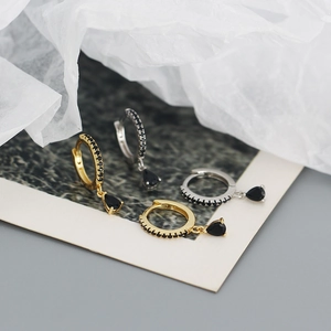 Detailed view of silver and gold drop earrings with black stones and pavé micro-inlay