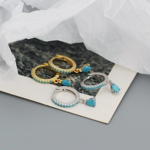 Macro shot of silver and gold drop earrings with turquoise stones and blue crystals