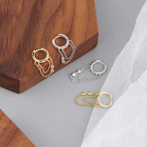 Detail of silver and gold tassel hoop earrings with sparkling zircon drop chains