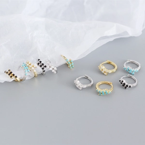 Dettaglio di orecchini huggie in argento S925 con zirconi colorati e design geometrico