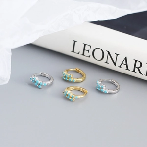 Dettaglio di orecchini a cerchio geometrici in oro e argento con perline turchesi