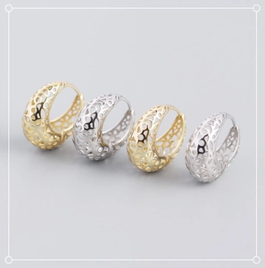Detailed view of hollow geometric earrings in gold and silver finishes on gray surface