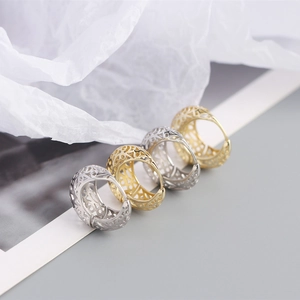 Macro shot of silver and gold hollow geometric earrings with intricate vintage engraving