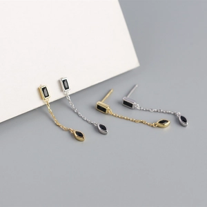 Détail de boucles d'oreilles géométriques à glands avec pierres noires en or et argent