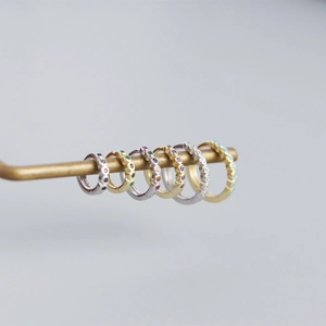 Detailed macro shot of colorful gemstone pavé huggie hoop earrings in gold and silver plating