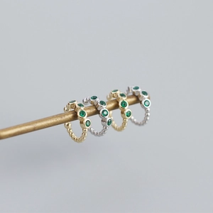 Set of gold and silver ear cuffs featuring green emerald stones and beaded metal texture