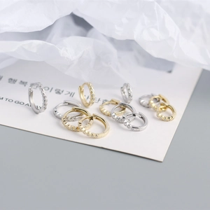 Detailed view of silver and gold huggie earrings with cubic zirconia on display card