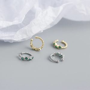 Macro view of S925 sterling silver ear cuffs with green stones and beaded edges