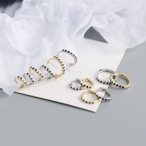 Macro shot of minimalist gold and silver S925 sterling silver hoop earrings with black stones
