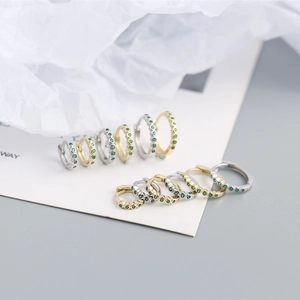 Macro shot of 925 silver hoop earrings with paved green zircon stones in gold and silver