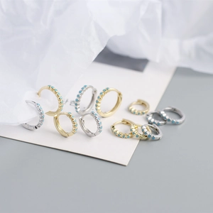 Detail of S925 sterling silver huggie earrings with turquoise stones in gold and silver