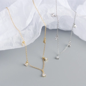 Detail of minimalist 925 sterling silver necklaces with tiny zircon charms in gold and silver