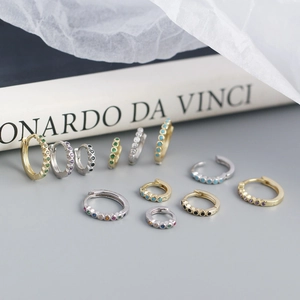 Minimalist S925 silver huggie earrings with colorful zircon stones on artistic book background