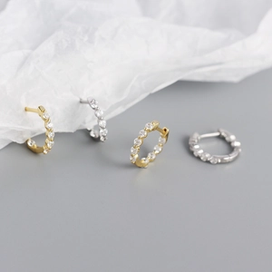 Détail de boucles d'oreilles huggie argent et or avec zircons micro-pavés sur gris