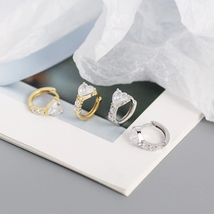 Macro view of gold and silver heart-shaped hoop earrings with sparkling zircon stones