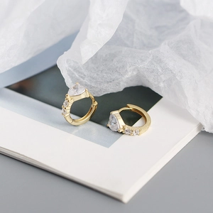 Detailed close-up of a gold heart hoop earring featuring a central zircon and diamond accents